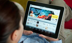 Woman using iPad tablet computer at home to browse iTunes digital music store